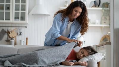 Mom tucks in kid to bed