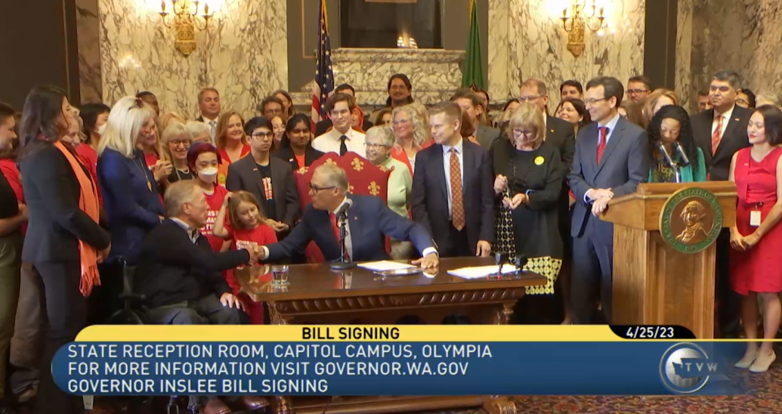Jay Inslee shakes the hand of a participant at the signing of HB 1240 to ban assault weapon sales in Washington