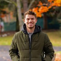 Jeff stands in a park, in front of a tree changing colors